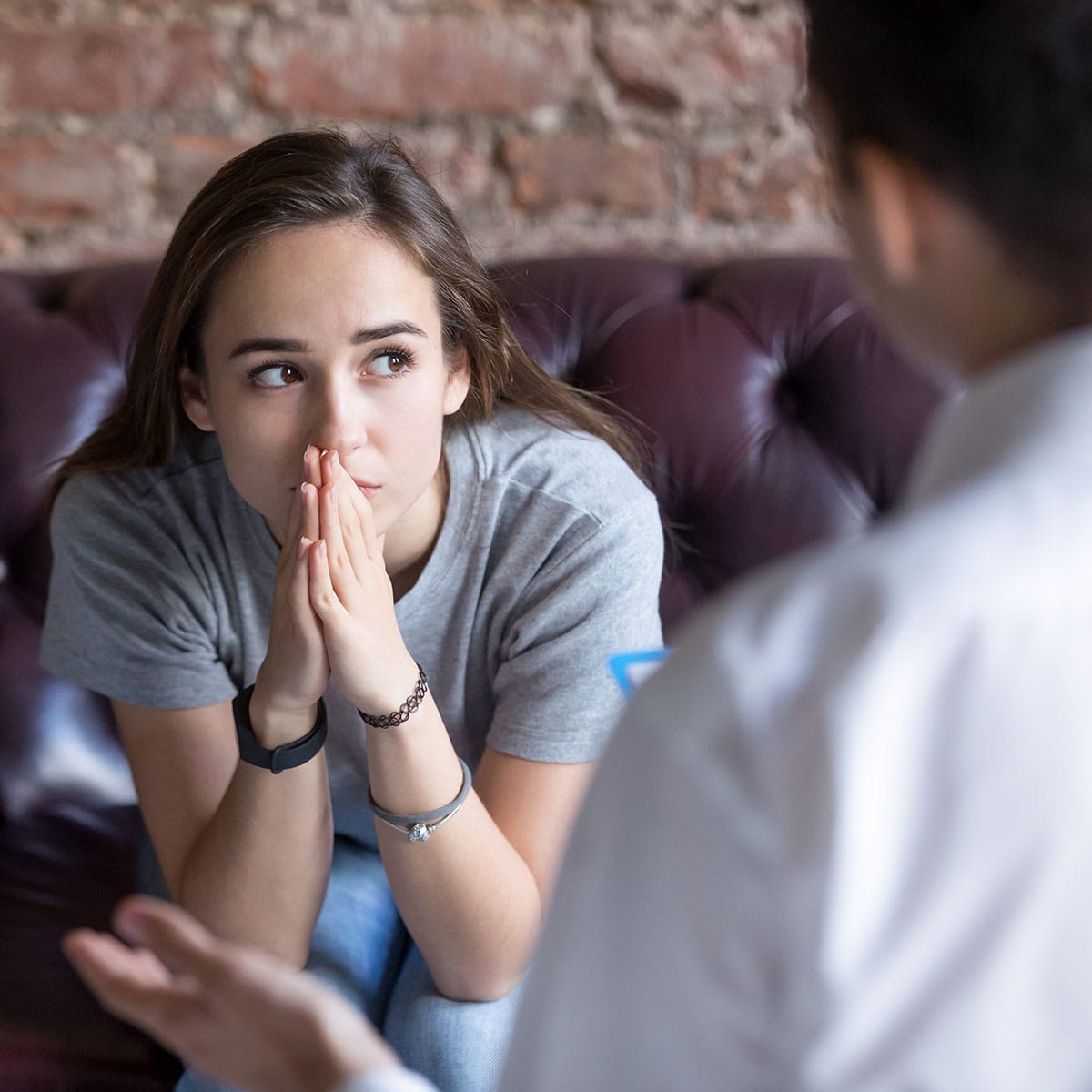 Concerned person with hands pressed together while talking to a counselor at QuickSilver Counseling Center