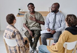Happy person engaging with a group of people in therapy in a rehab treatment program
