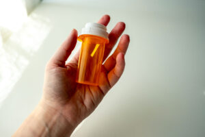 a person holds a pill bottle wondering about the differences between opioid vs. opiates